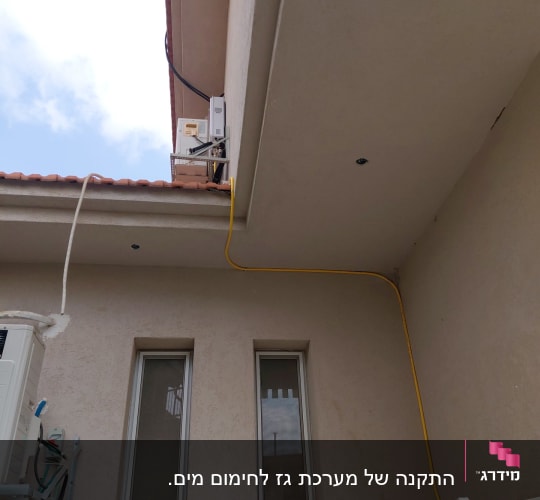 התקנת צינור גז צהוב ומחמם מים בגז על קיר חיצוני